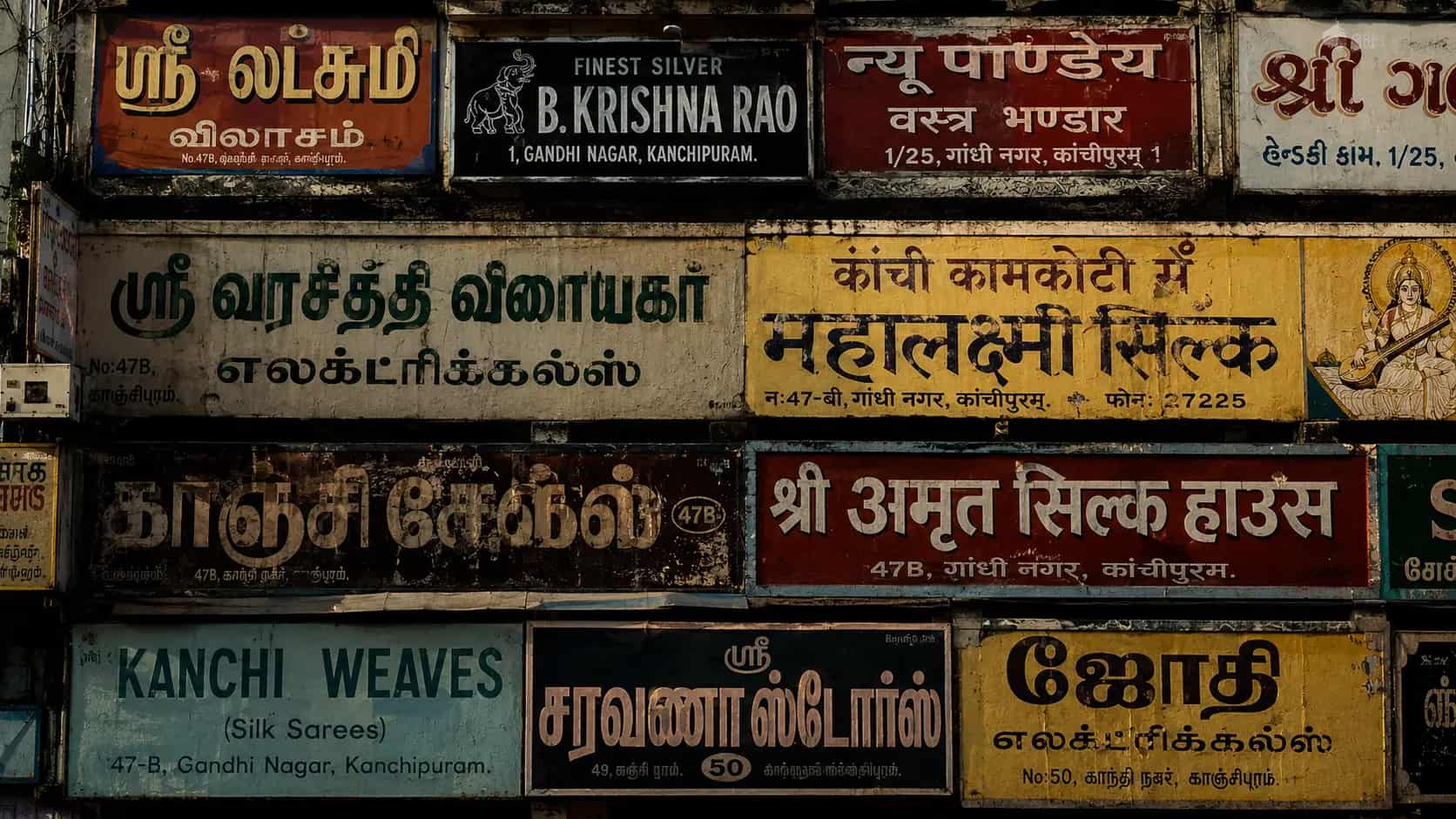 A wall of hand-painted shop signboards in Tamil, Hindi, Gujarati and English